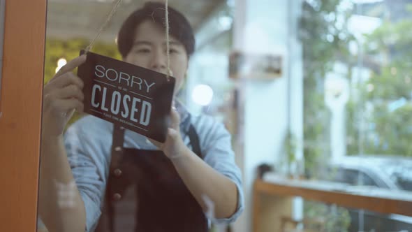 Business owner asian man turning Welcome we are open sign on fronton glass door store.