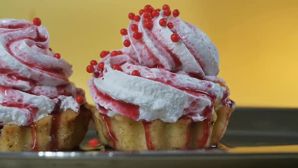 Sprinkle Round Pastry Red Balls of Decoration on Two Cakes with Cream Poured with Sweet Berry Syrup