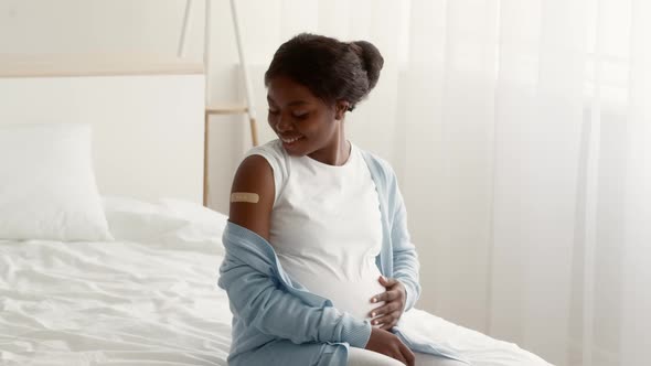 Vaccinated Black Pregnant Woman Looking At Arm With Adhesive Bandage After Vaccination