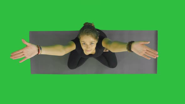 Portrait of Attractive Young Woman Working Out, Sitting in Lotus Position with Palms in Namaste