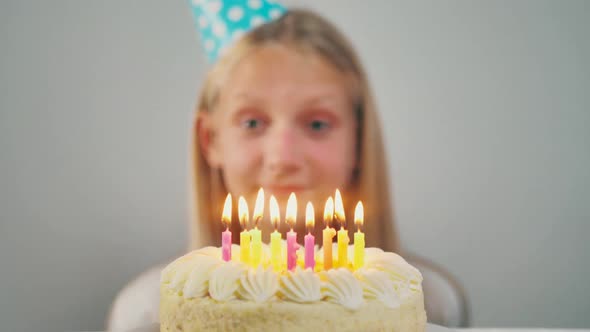 Closeup of an Adorable Little Girl with Closed Eyes Making a Wish and Blowing Out Candles on a