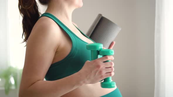 A Pregnant Woman Prepare for Exercising with Dumbbells