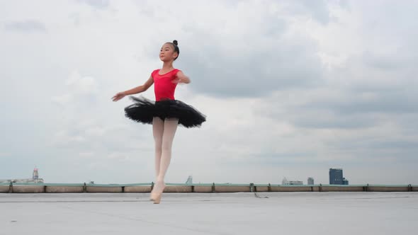 Ballet girl with red dress and black skirt dance on rooftop or terrace of high building in big city