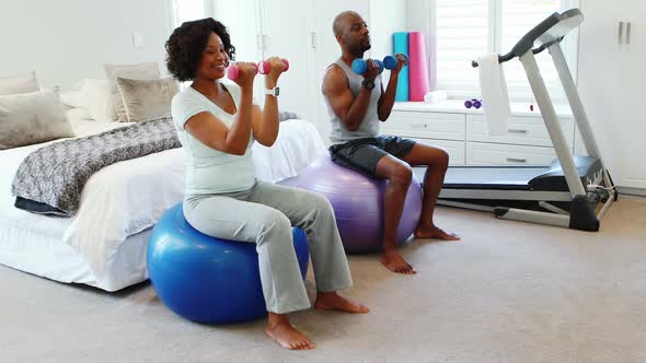 Couple exercising with dumbbells on exercise ball 4k