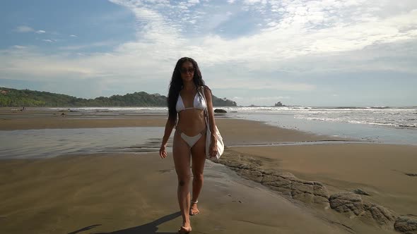 Beautiful female model walking in slow motion on tropical sand beach