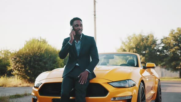 Confident African Man in Business Suit Standing Near Luxury Car with Modern