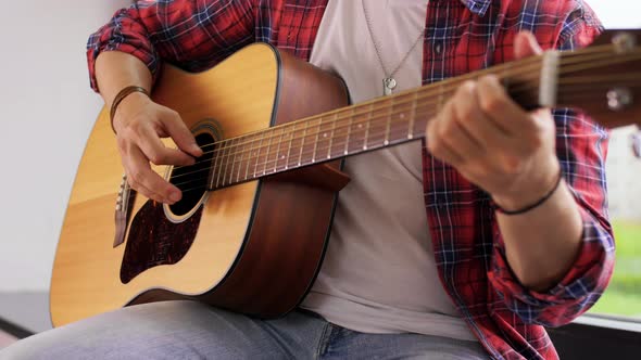 Young Man Playing Guitar Sitting on Windowsill