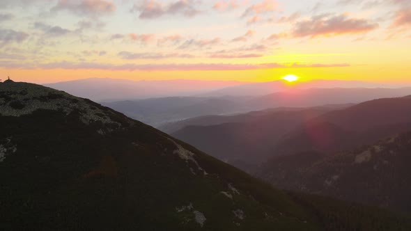 Aerial View of Foggy Evening Over High Peak with Dark Pine Forest Trees at Bright Sunset