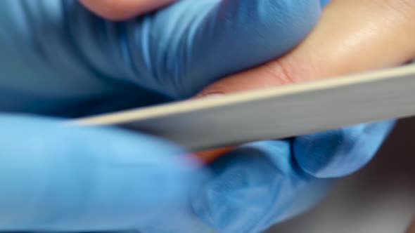 Manicure Saws the Nail of Client By Nail File. Close Up