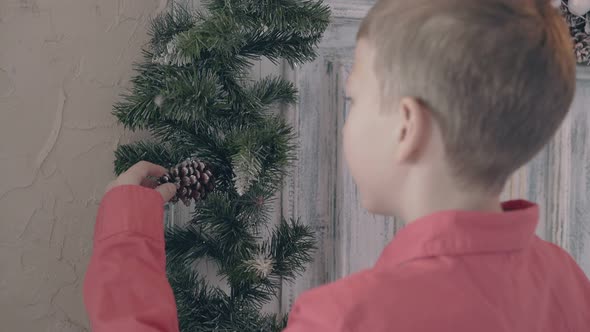 Blond Son Watches Pine Cone on Christmas Themed Decoration