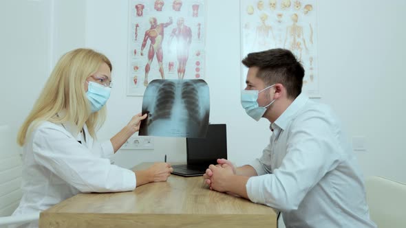 Female Doctor with Glasses in Medical Mask Checking Xray Lungs Consulting a Patient Positive for