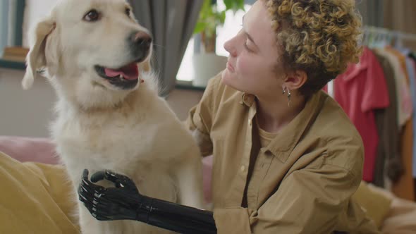 Young Woman with Prosthetic Arm Petting Dog at Home