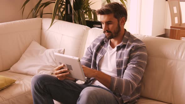 Man relaxing on sofa and using digital tablet