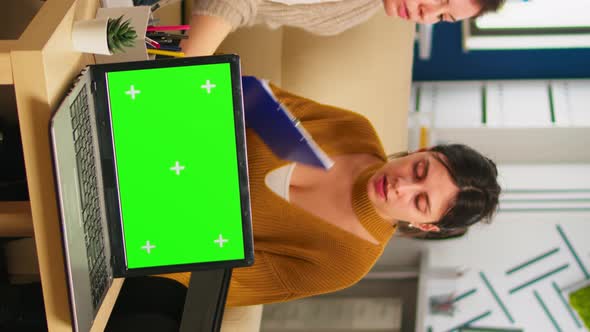 Diverse Women Sitting at Table Discussing Strategy with Green Screen Laptop