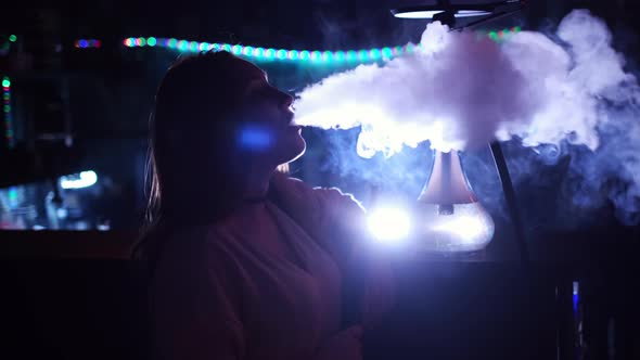 Girl smoking hookah on blue neon background