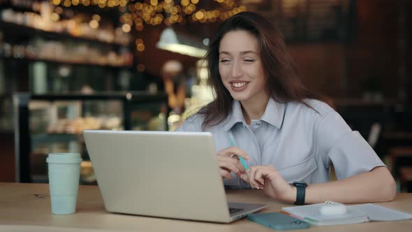 Positive Woman Having Online Lesson on Laptop at Cafe