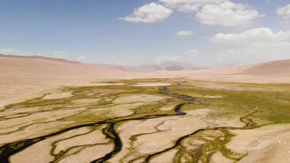 Top Aerial View of a Nearly Dry River Crossing Desert in Tajikistan Blue Sky in Background