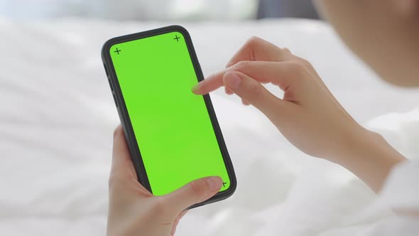 woman holding in hands a mock up smartphone with green screen for internet online.