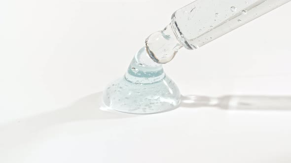 Macro Shot of Transparent Blue Cosmetic Fluid Gel Cream With Bubbles in Pipette Drips on a White