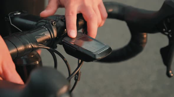 Cyclist pushing start button on GPS gadget, recording track and starting to ride on bicycle.