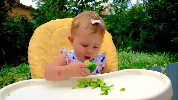 Baby is Eating Pieces of Broccoli