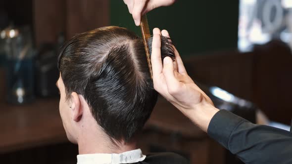 Barber Trimming Client's Hair Using Tools in Shop