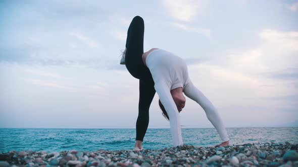 A Woman Standing on the Bridge Posture on the Pebble Beach