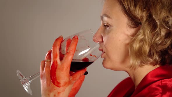 Woman Drinks Red Wine From Glass Stained with Blood Closeup