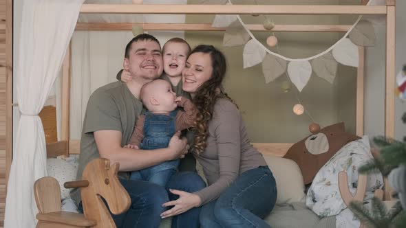 Happy Family of Four Hugging on Bed at Home