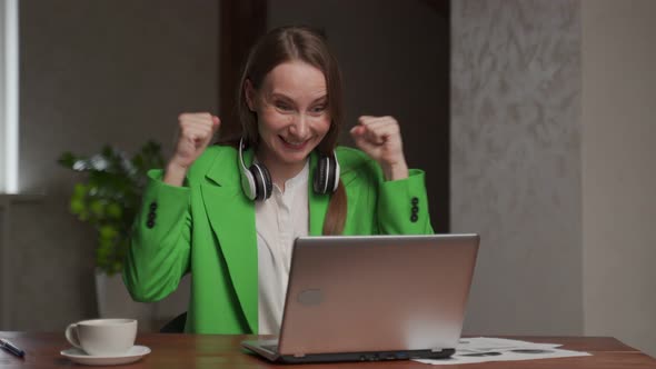 Woman with Headphones on Neck Watches Competition on Laptop