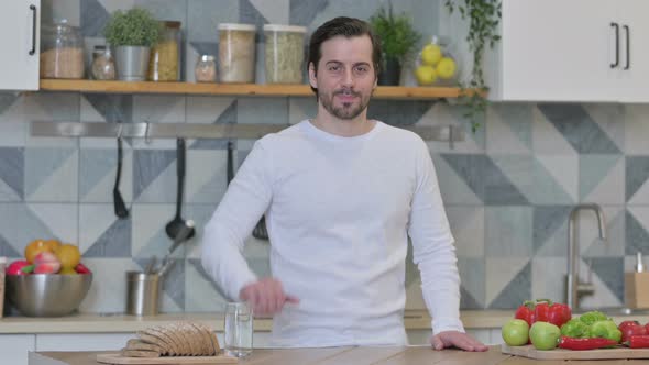 Young Man Showing Thumbs Down While Standing in Kitchen