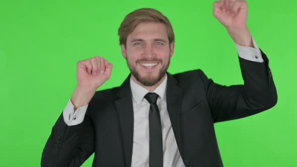 Young Businessman Dancing in Joy on Green Background