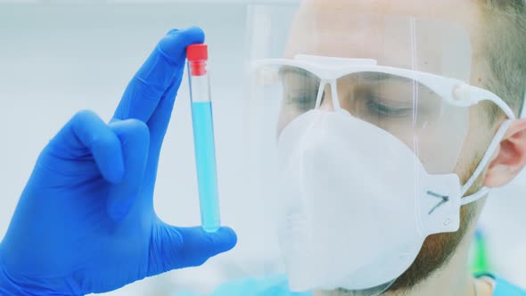 A Doctor or Scientist in the Laboratory Is Holding a Test Tube with a Blue Liquid