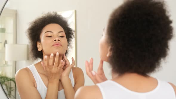 African american black woman looking touching face in the mirror examining skin condition