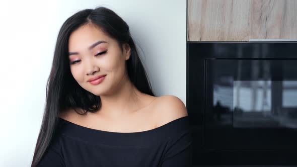 Playful Cute Asian Young Woman with Naked Shoulders Posing and Looking at Camera in Modern Kitchen