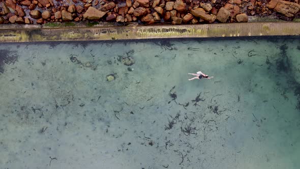 Aerial view of woman swimming in Glencairn pool, Cape Town, South Africa.