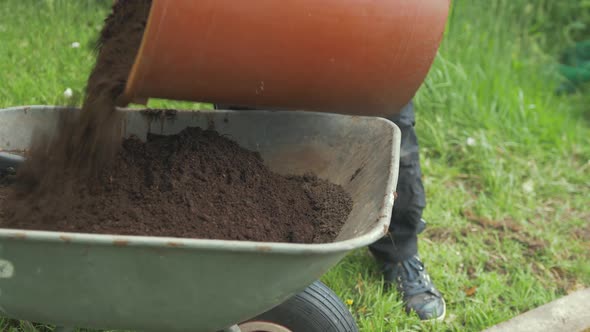 Pouring soil from bucket into wheelbarrow