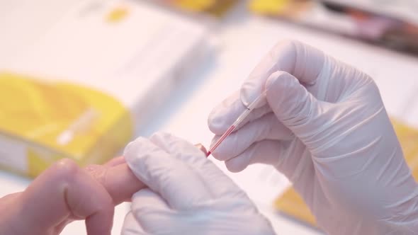 Closeup Anonymous Medical Practitioner in Latex Gloves Piercing Finger and Taking Blood Sample From