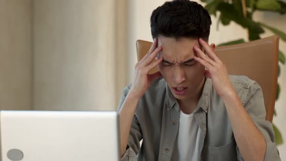 Asian Employee Holds Head Trying to Solve Difficult Issue