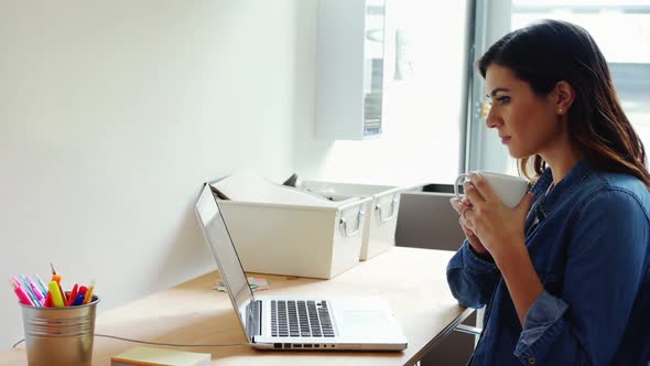 Female executive using laptop white having coffee