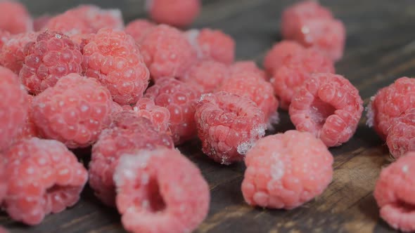 Man Pours Frozen Raspberries on a Wooden Table. Frozen Raspberries Are Poured Onto a Wooden Board