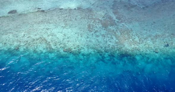 Tropical fly over clean view of a white paradise beach and aqua blue ocean background in colorful 4K