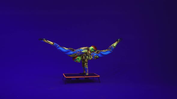 Twins Acrobats Perform A Pair Of Gymnastic Elements On A Blue Cyclorama,Neon Makeup And Costumes