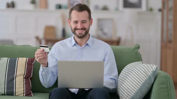 Online Shopping Success on Laptop for Young Man on Sofa