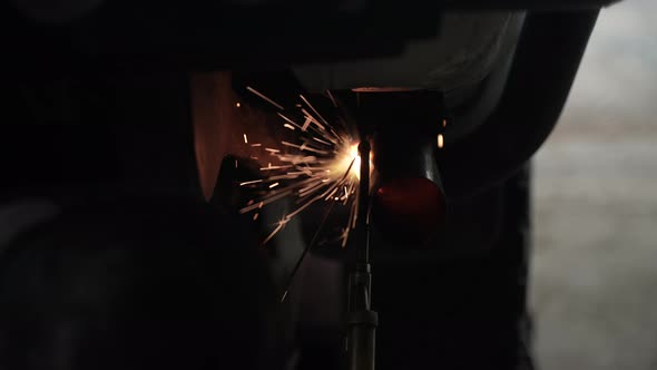 blacksmith welder works with metal steel and iron using a welding machine, bright sparks and flashes