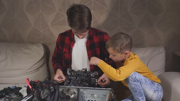 Teenager Holds a Computer Board in His Hand and Shows It To His Younger Brother. It Shows What Is