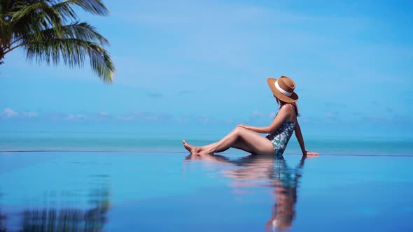 Young woman traveler relaxing and enjoying by a tropical resort pool