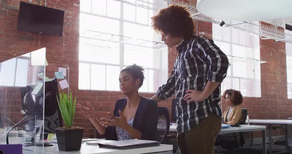 Diverse male and female colleagues discussing over computer screen in office