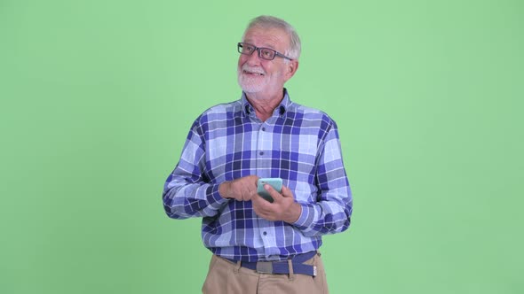 Happy Senior Bearded Hipster Man Thinking While Using Phone