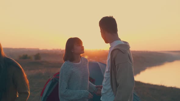 Lovely Couple Joins Hands Near Tent and Friends in Camp